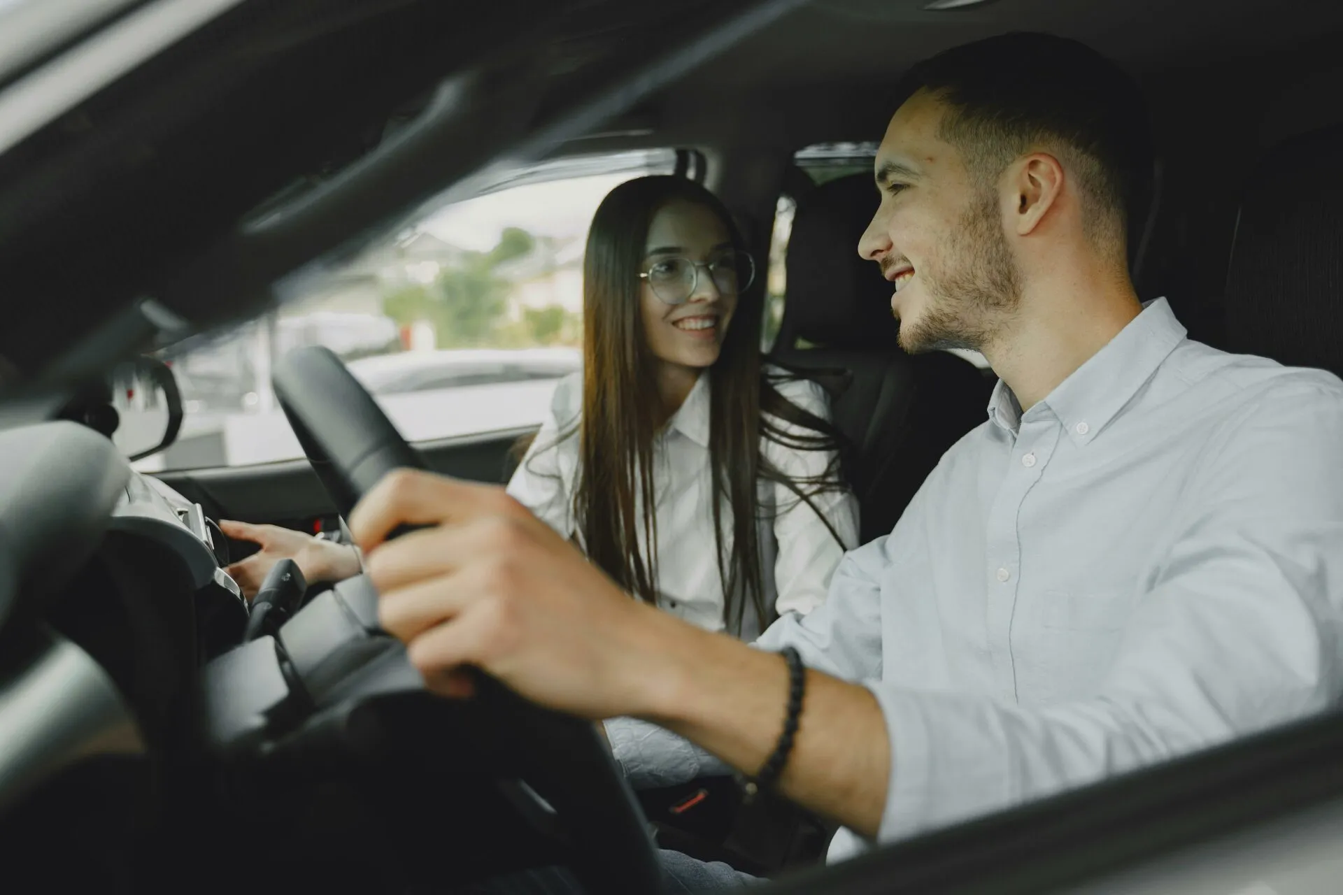 Driving instructor and learner smiling inside car