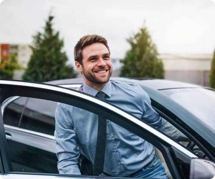 Smiling driving instructor standing next to a car